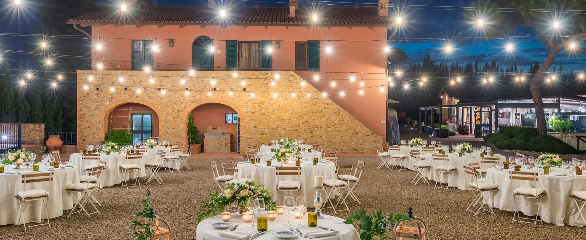 Elegant dinner table set outdoors with candles and decorative lighting