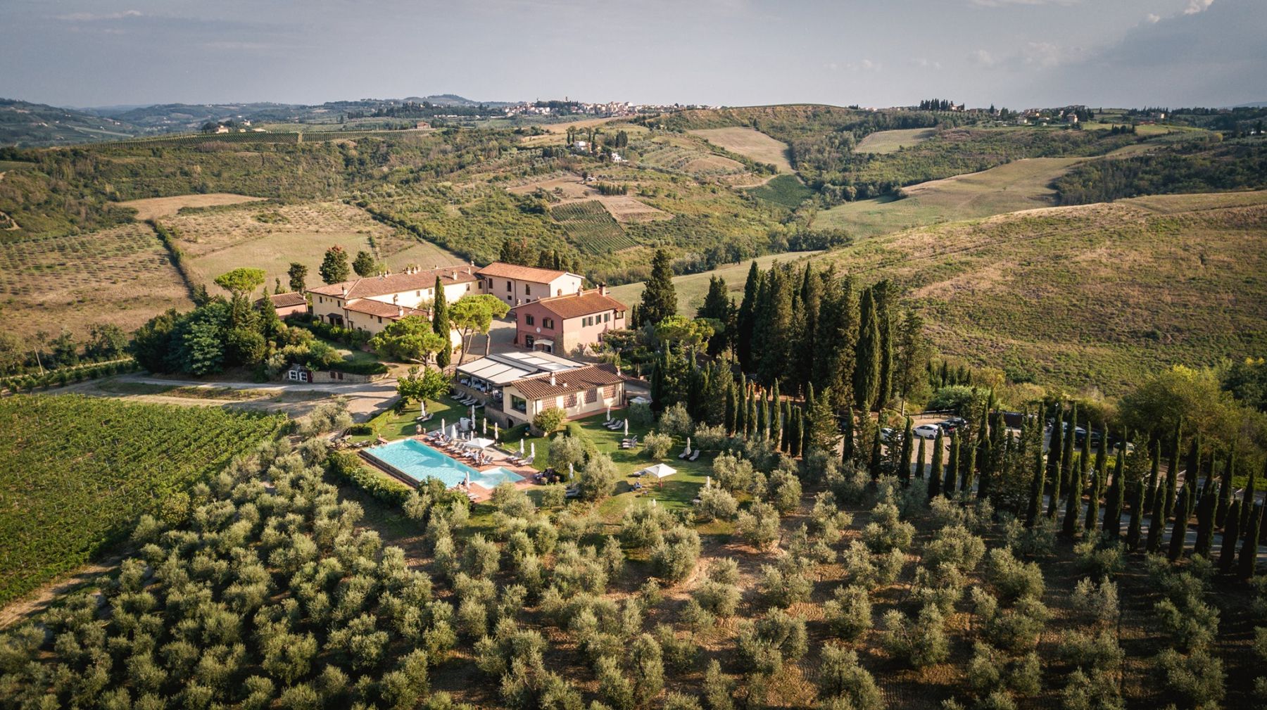 Aerial view of Borgo Divino surrounded by olive groves, cypress trees and the Tuscan hills
